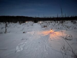 Snow trail lit by lanterns at dusk